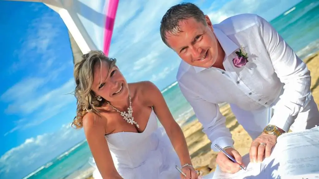 a bride and groom signing their wedding papers on the beach.