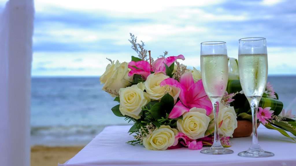 two glasses of champagne on a table next to a bouquet of flowers.